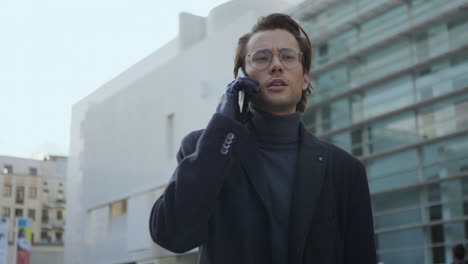 Serious-businessman-talking-on-phone-at-street.-Employee-walking-for-meeting