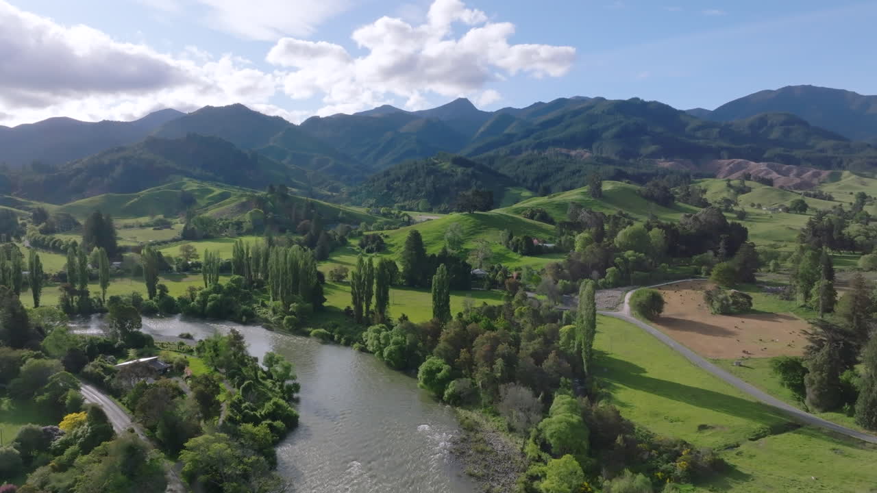 Stunning aerial drone shot soaring over the rolling green hills and winding river in the Motueka Valley, New Zealand