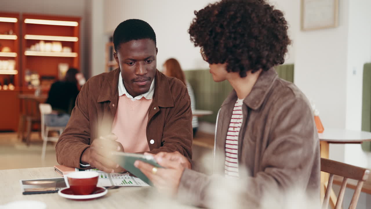 Two men collaborating in a cafe with a tablet