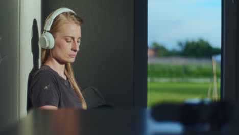 una mujer contemplativa y pensativa escucha música con auriculares.