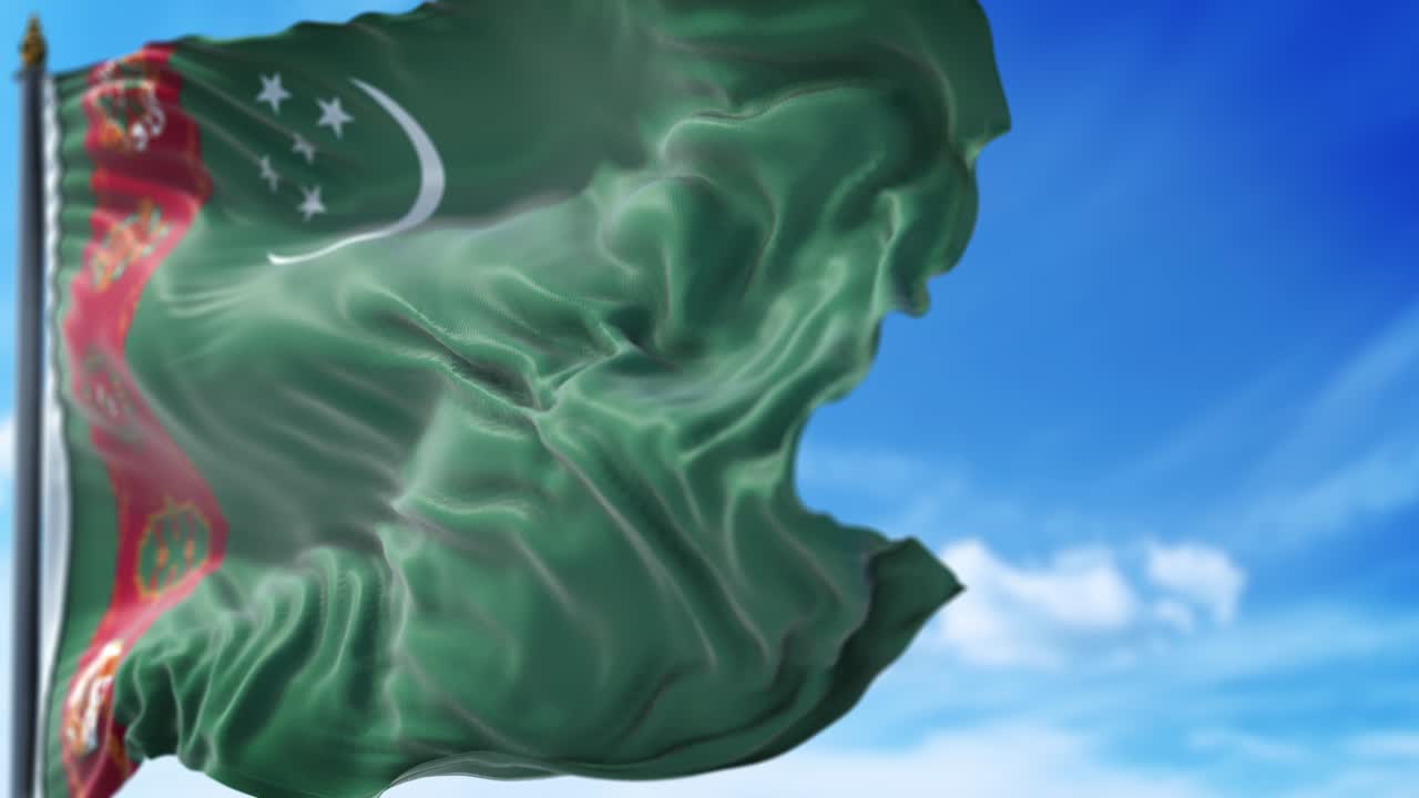 la bandera de turkmenistán está ondeando lentamente contra el cielo azul