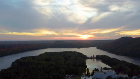 Puesta-De-Sol-Dorada-Sobre-El-Lago-Del-Bosque-Y-Una-Enorme-Mansión,-Vista-Aérea-Ascendente