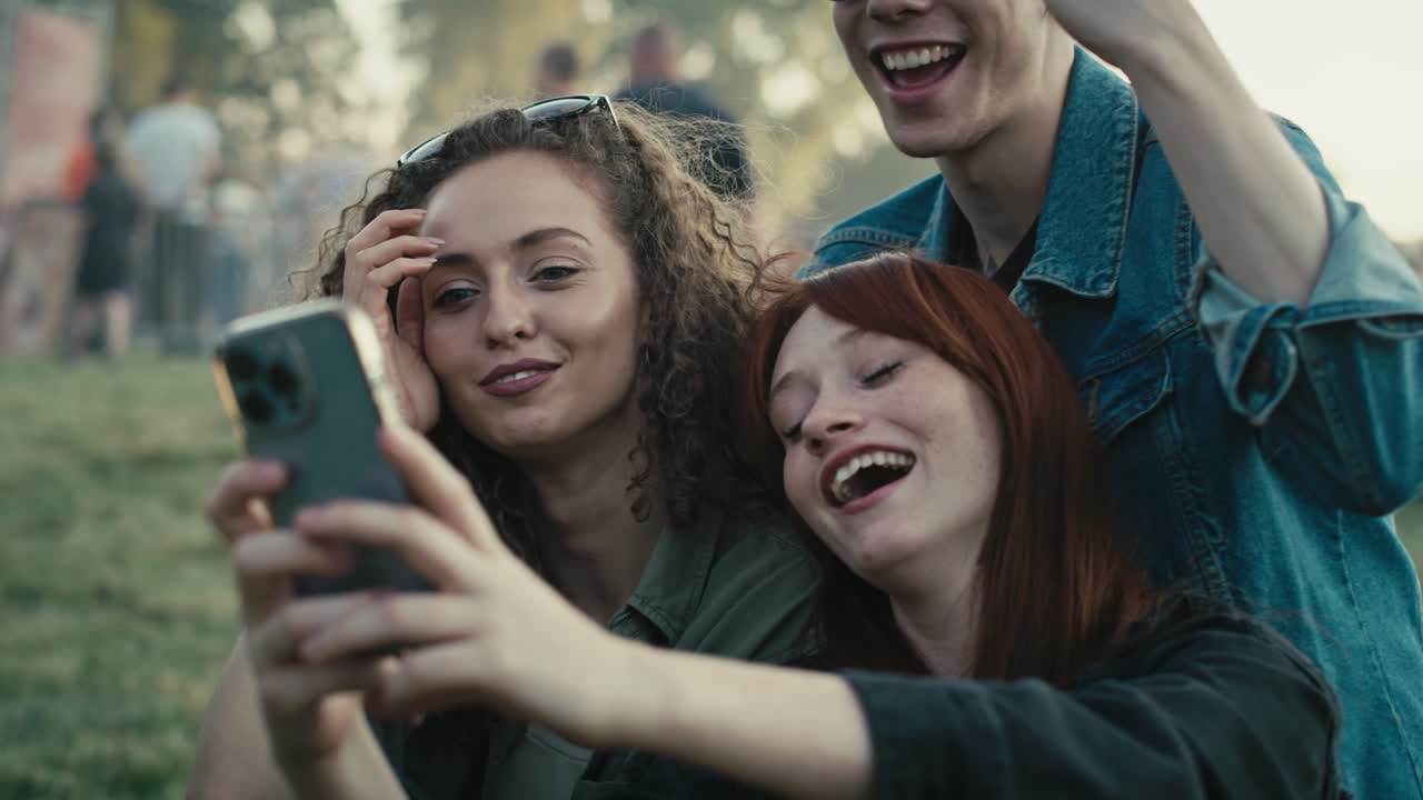 Gruppo di amici caucasici che fanno facce buffe per un selfie di gruppo a un festival musicale.