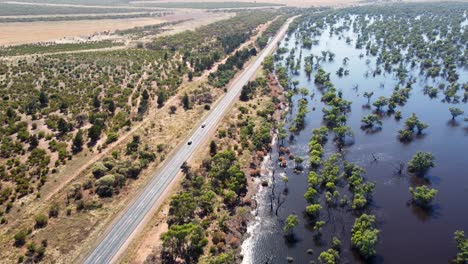 Aerial-drone-bushland-flooding-with-car-driving-on-freeway-highway-outback-Victoria-Mildura-nature-landscape-tourism-travel-4K-Australia