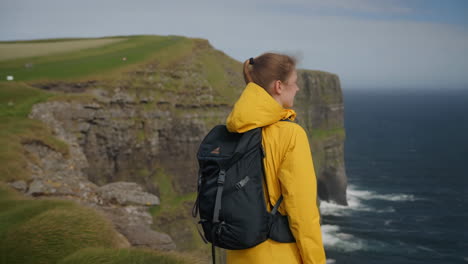 woman hiking on the cliffs of moher overlooking the ocean