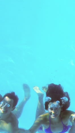 four friends jumping into swimming pool and waving