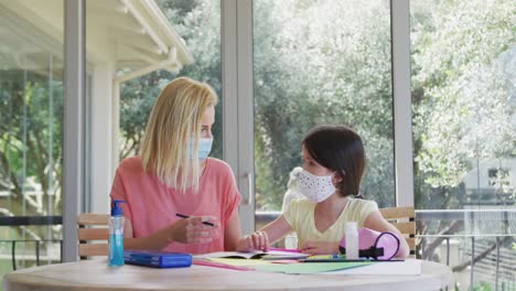 Mother-wearing-face-mask-helping-daughter-with-homework-at-home