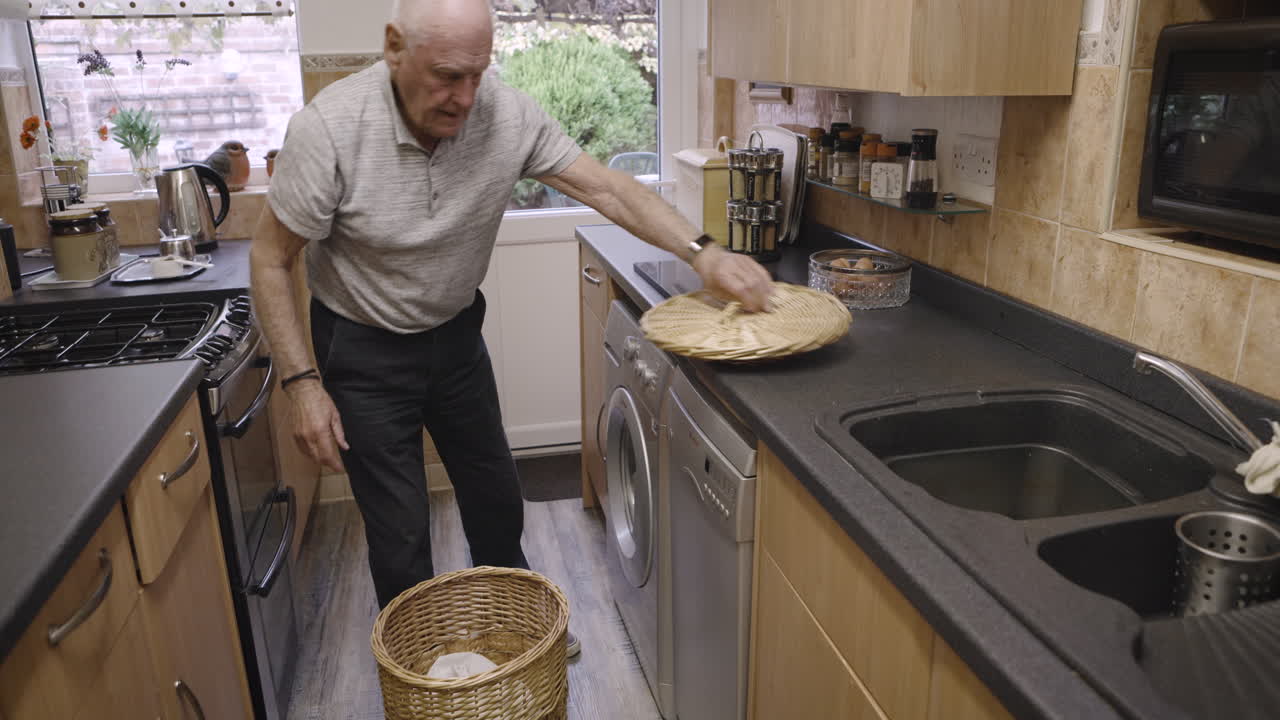 Elderly man doing laundry in kitchen
