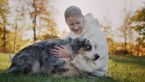 The-owner-gently-strokes-his-dog-in-the-sun.-Sits-next-to-a-pet-on-the-grass-in-the-park