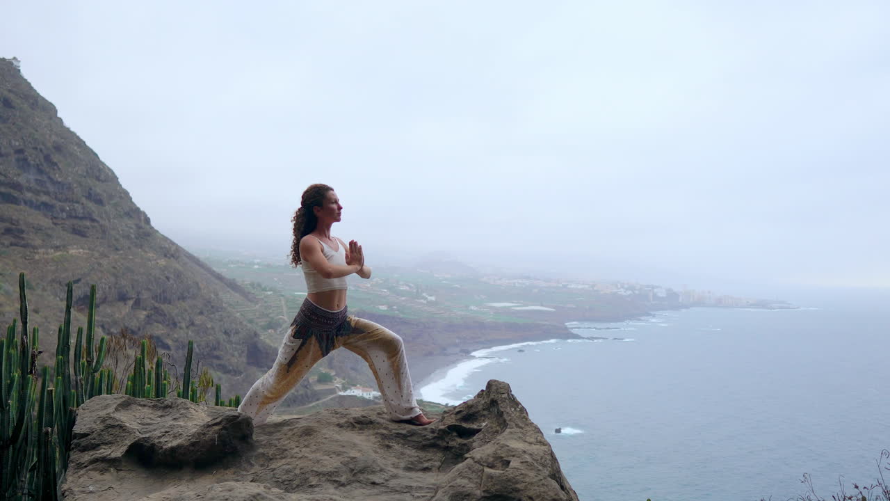 una mujer joven practica yoga en una playa rocosa durante la puesta de sol, en medio del océano azul, simbolizando el concepto de un estilo de vida saludable, armonía y la coexistencia de los humanos y la naturaleza