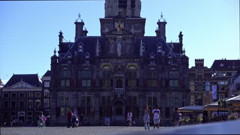historic old town hall in delft, netherlands with people in the square
