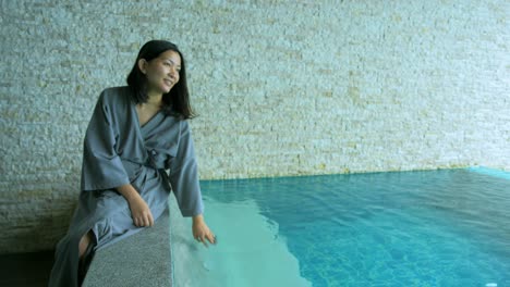 Der-Weiche-Und-Verschwommene-Fokus-Asiatischer-Frauen,-Die-Am-Privaten-Pool-Im-Resort-Sitzen-Und-Ihre-Hand-Benutzen,-Um-Im-Urlaub-Das-Wasser-Zu-Spritzen