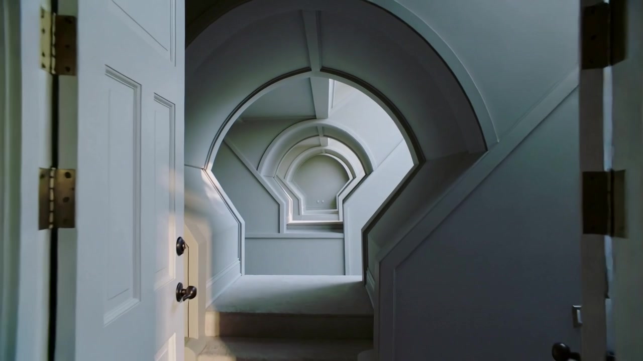Porta a battente leggermente socchiusa che rivela nicchie ad arco annidate nel corridoio, con la telecamera che avanza.