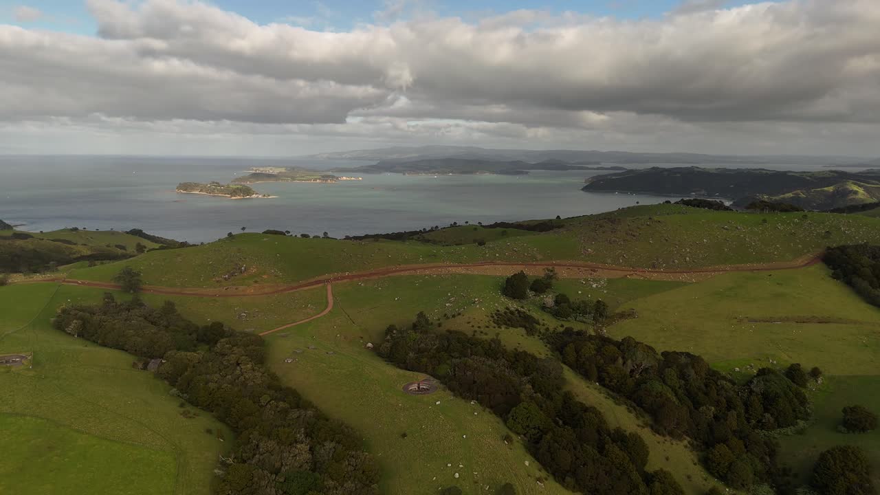 A stunning 4K 60fps aerial view of the sprawling Stony Batter Historic Reserve on New Zealand's Waiheke Island, capturing the WWII fortress ruins amidst rolling green hills and rugged coastline