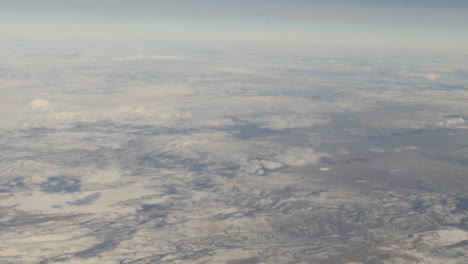 aerial view of snow capped mountains out of from flying airplane window shot in 4k high resolution