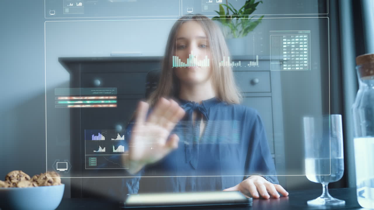 mujer joven que opera un holograma a partir de una tableta en la mesa en la oficina del hogar