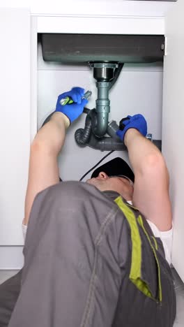 a Worker in Protective Work Clothes is Doing Plumbing Work Replacing an Old Broken Sink Filter a Worker in Protective Work Clothes is Doing Plumbing Work Replacing an Old Broken Sink Filter call the Master Plumber to the House