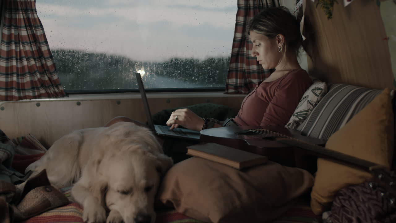 Donna che usa il laptop in camper in una giornata di pioggia