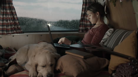 woman using laptop in camper van on rainy day