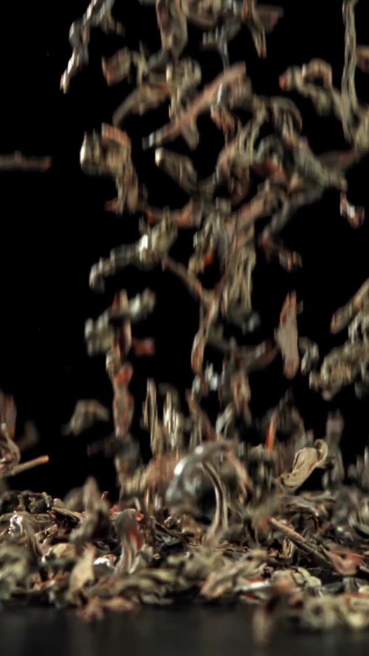 Dry Tea Leaves Falling in Slow Motion on Black Background