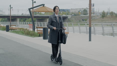 businessman riding an electric scooter in a city park