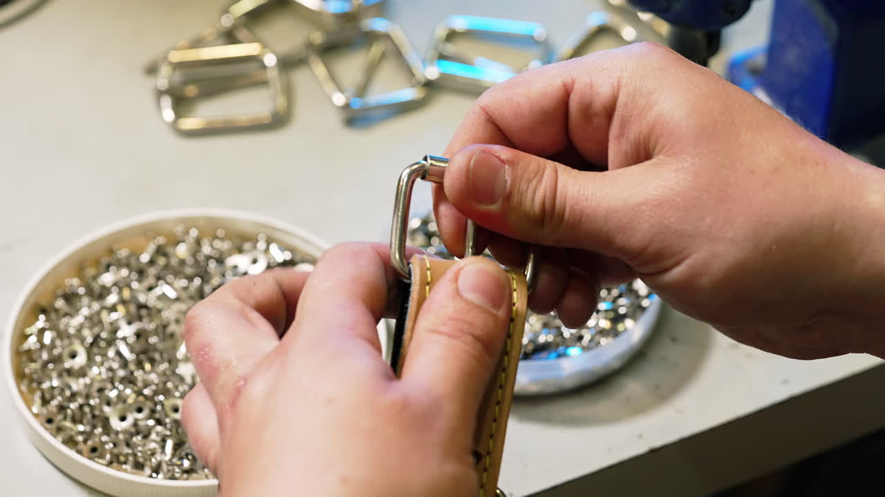 Fashion master is working on exclusive leather accessories. Tailor sews a belt with a special equipment in workshop.