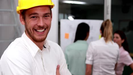 casual businessman smiling at camera with team behind him