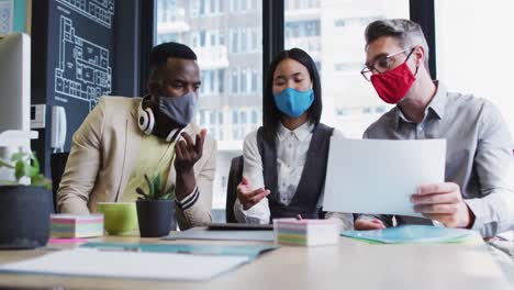 diverse office colleagues wearing face masks discussing together at modern office