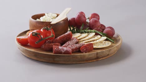 Galletas-Crujientes,-Tomates,-Uvas-Y-Plato-De-Queso-Sobre-Tabla-De-Madera