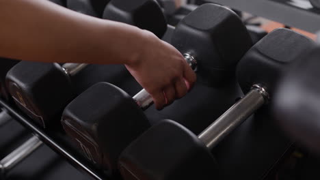 person handling dumbbells in a gym