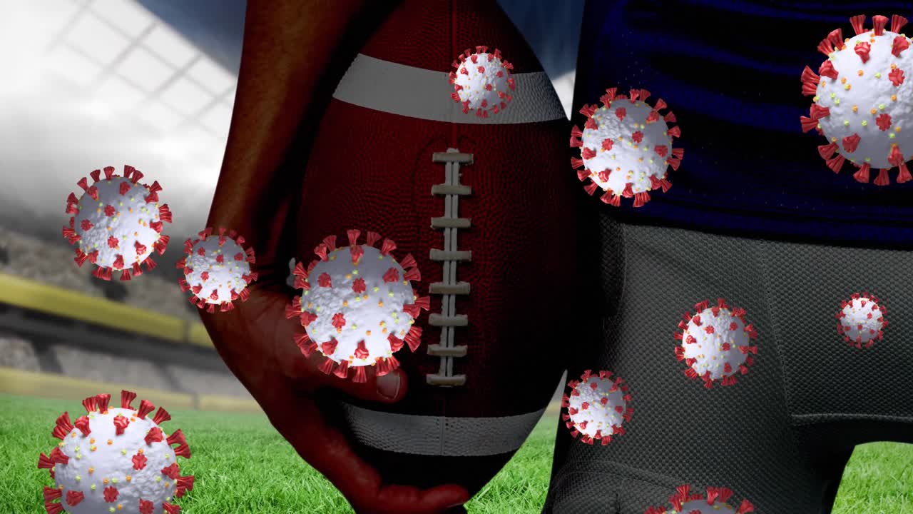 코로나19 세포가 스포츠 경기장을 향해 공을 들고 있는 남자 럭비 선수의 중간 부분에 떠다니고 있습니다.