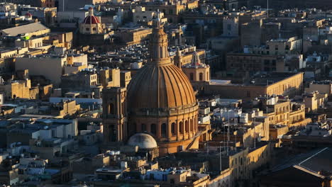 Toma-Aérea-De-Teleobjetivo-Orbitando-La-Basílica-De-Nuestra-Señora-Del-Monte-Carmelo,-La-Valeta,-Puesta-De-Sol-En-Malta.