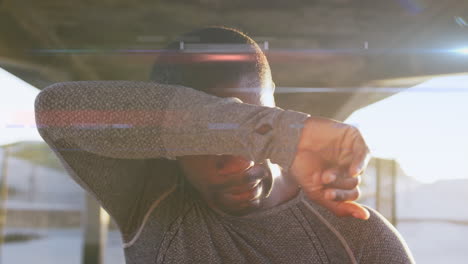 animation of glowing lights over running african american man taking a break, wiping brow in the sun