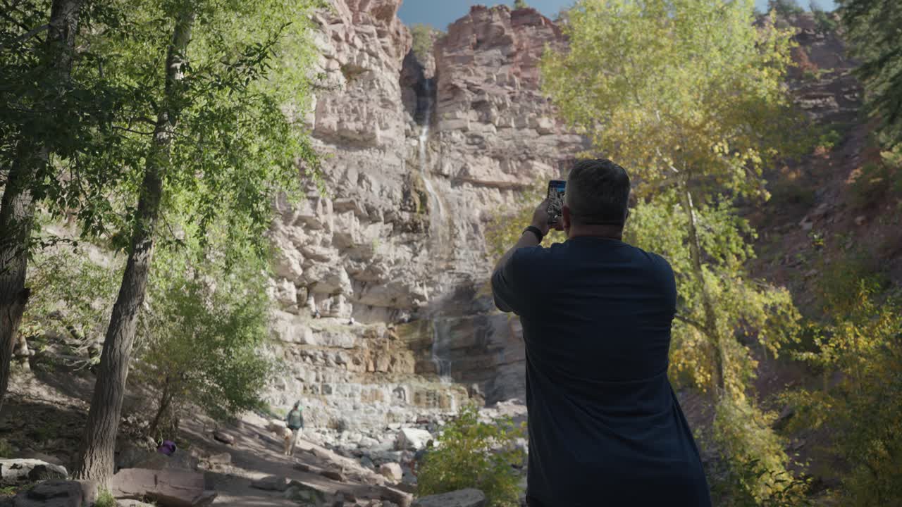 Man taking photo of waterfall