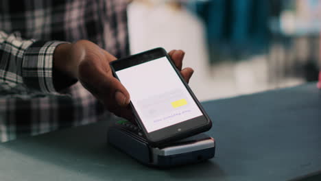 man putting mobile phone on pos terminal