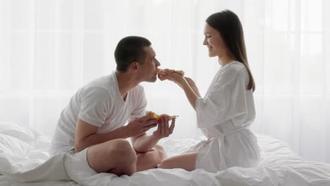 커플 이 침대 에서 아침 식사를 나누고 있다