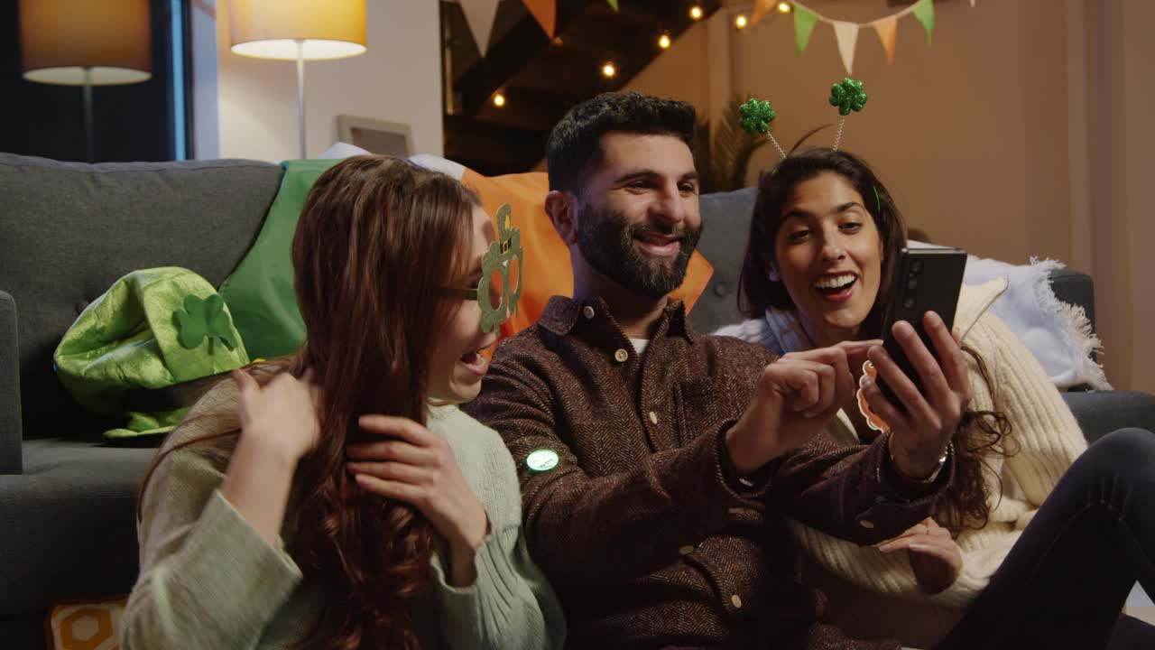 amigos disfrazándose con novedades irlandesas y accesorios en casa posando para selfies celebrando en la fiesta del día de san patricio 2