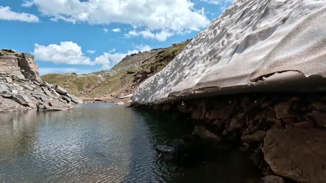 melting glacier edge touches a cold alpine pond surrounded by rocky slopes in alpe veglia natural park, italian alps