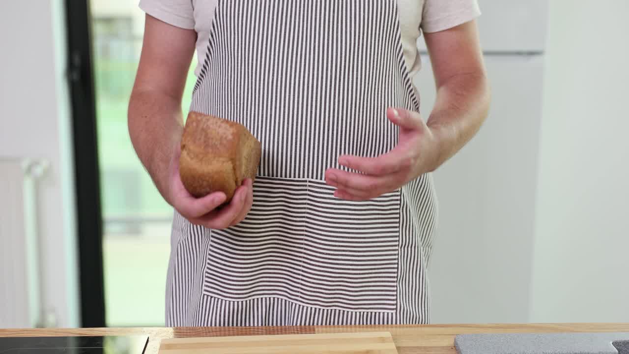 A person in an apron holding a loaf of bread