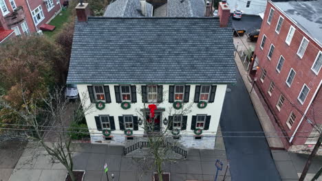 large restored home decorated for christmas holiday with wreath at each window lit by candle