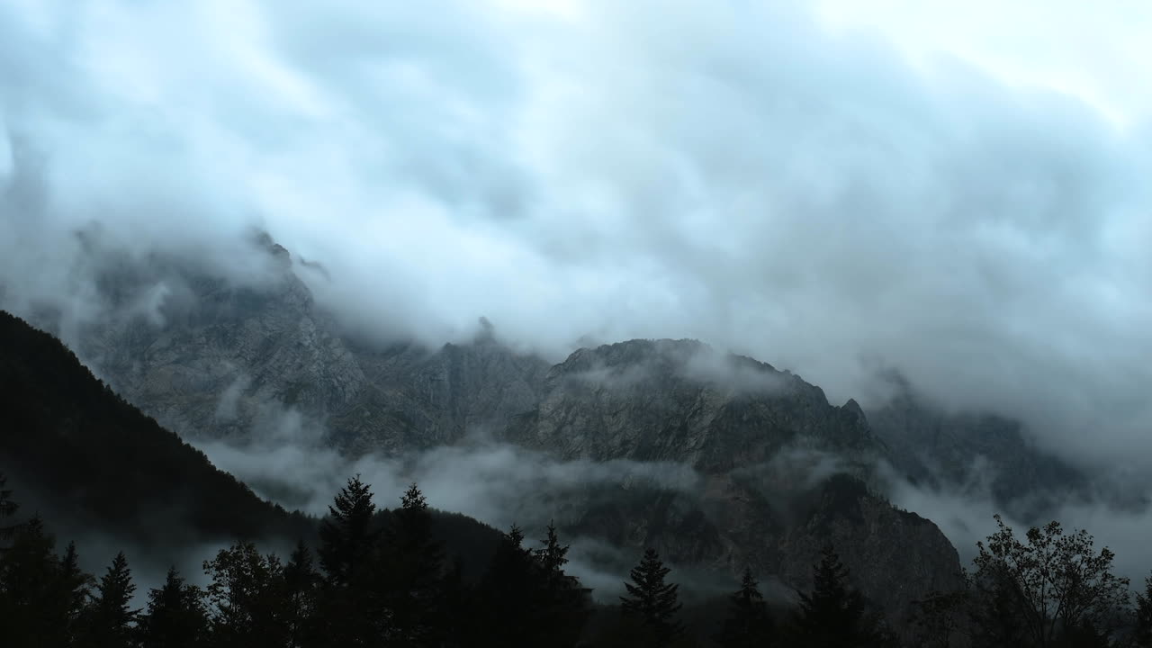 lapso de tiempo de las nubes sobre el pico de la montaña, cielo tormentoso dramático, bosque en primer plano, pico ojstrica en kamnisko savinjske alpe, logarska dolina, eslovenia, alpes europeos