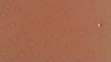 vista aérea de un vehículo de safari conduciendo a través de los famosos círculos de hadas de namibia