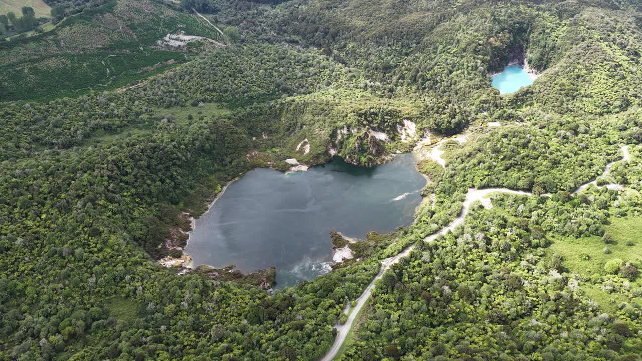Órbita de dron sobre lagos volcánicos y terreno exuberante en el Valle Volcánico de Waimangu, Nueva Zelanda, secuencias de geología y naturaleza cinematográfica