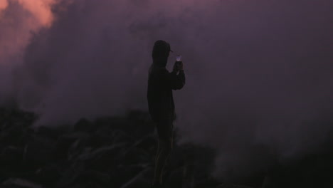 teenager films large wave breaking on jetty at sunset
