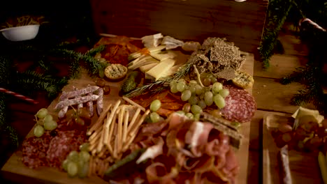 carnes curadas variadas, palitos de pan de uva y aperitivo de prosciutto en tabla de cortar con hierbas de romero, orbitan alrededor del tiro