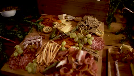 assorted cured meats, grapes breadsticks and prosciutto appetizer on cutting board with rosemary herbs, orbit around shot