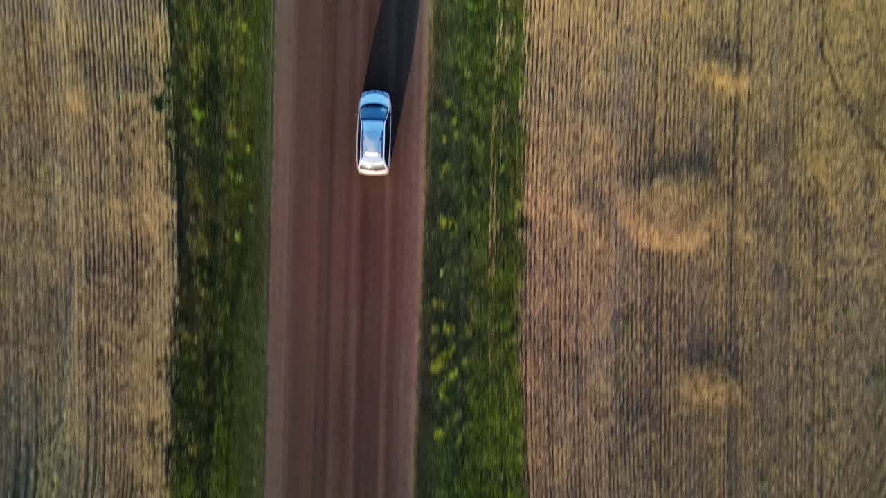 toma vertical aérea de una minivan conduciendo por un polvoriento camino de ripio en la zona rural de alberta, canadá