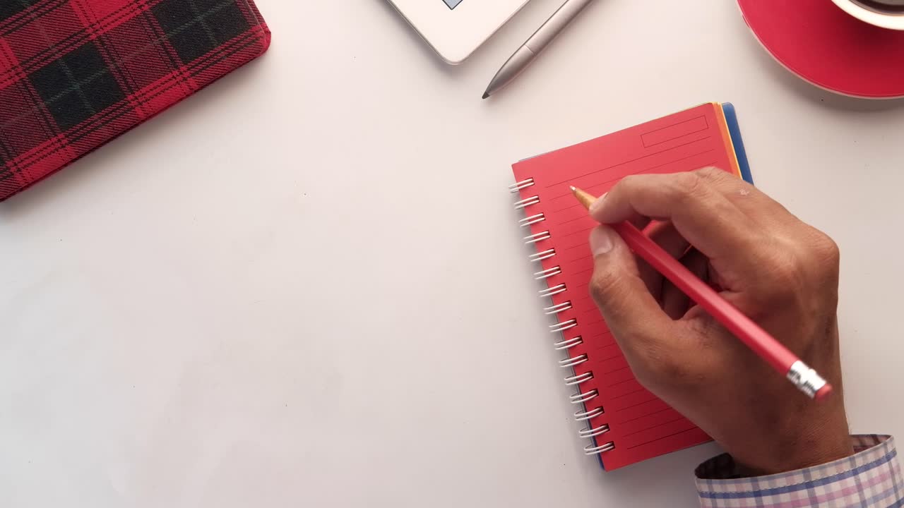 Person Writing in a Notebook with other Office Supplies