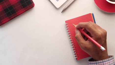 persona que escribe en un cuaderno con otros suministros de oficina