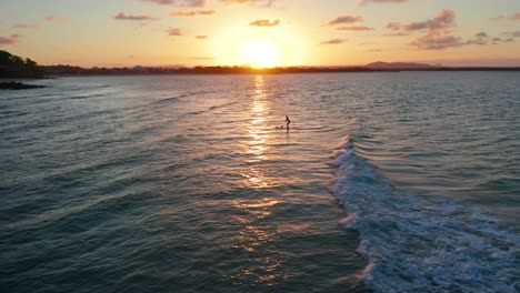 paddleboarder flotando y remando en el océano junto a la orilla